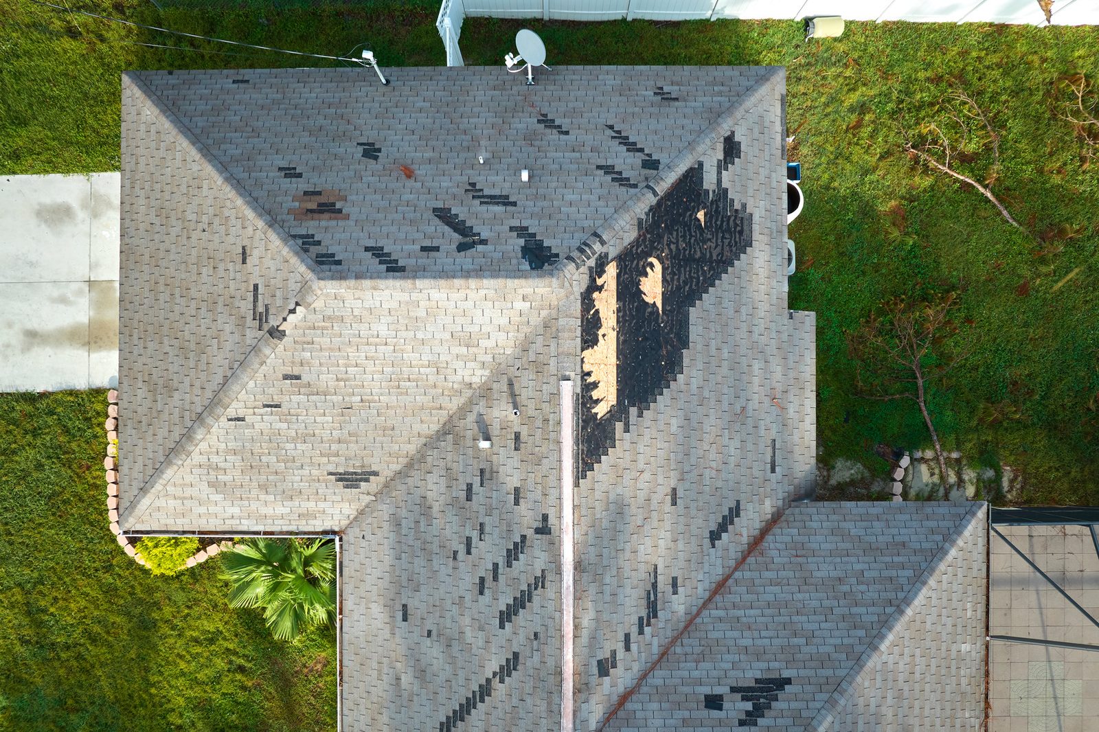 Storm-damaged roof with missing shingles and exposed decking